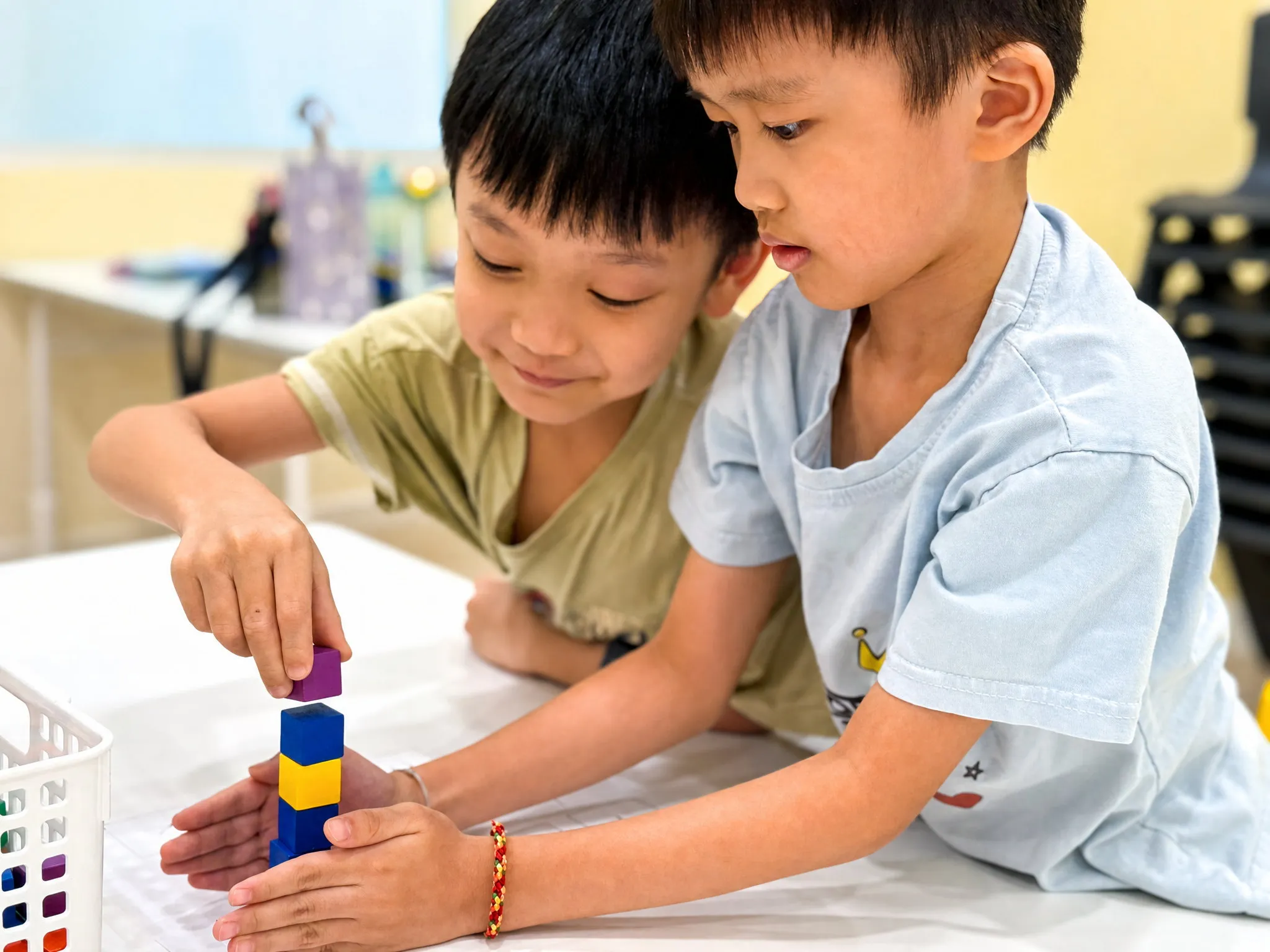 Two TITAN students building a tower of coloured cubes together at a table