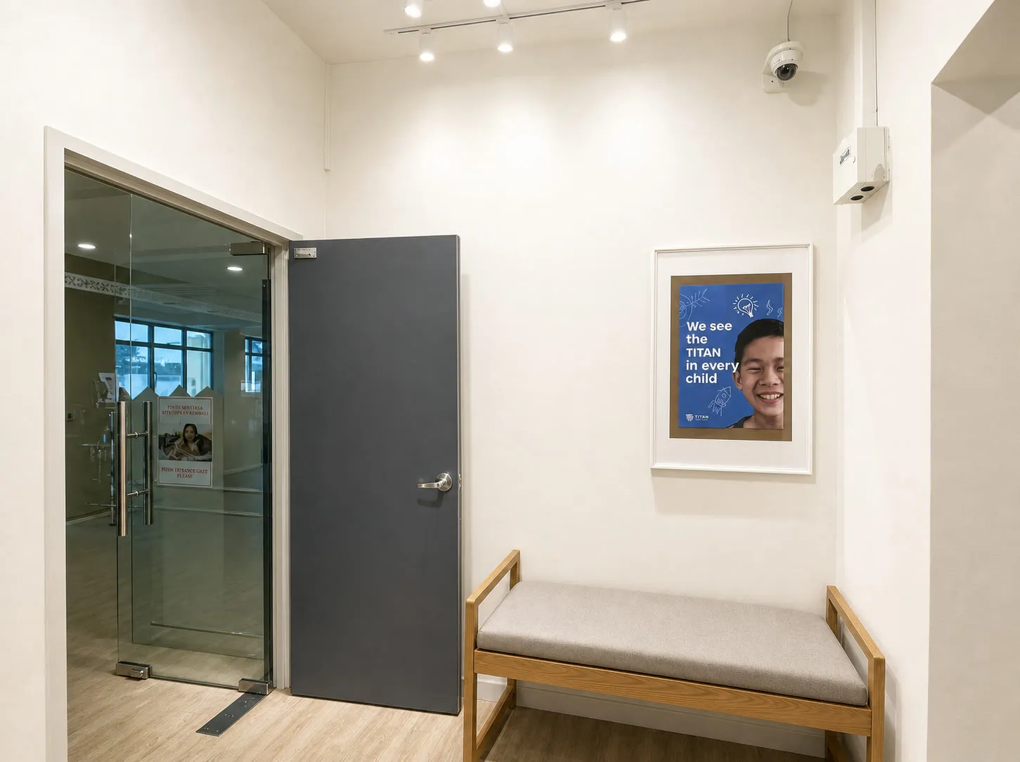 The entrance at the TITAN Taman Molek campus, with a framed poster reading “We see the TITAN in every child”