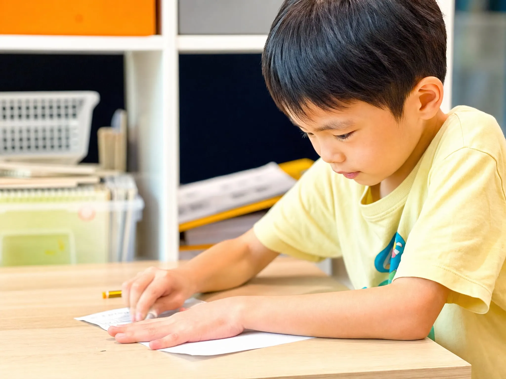 A TITAN student working through a written exercise at his desk, rubber in hand